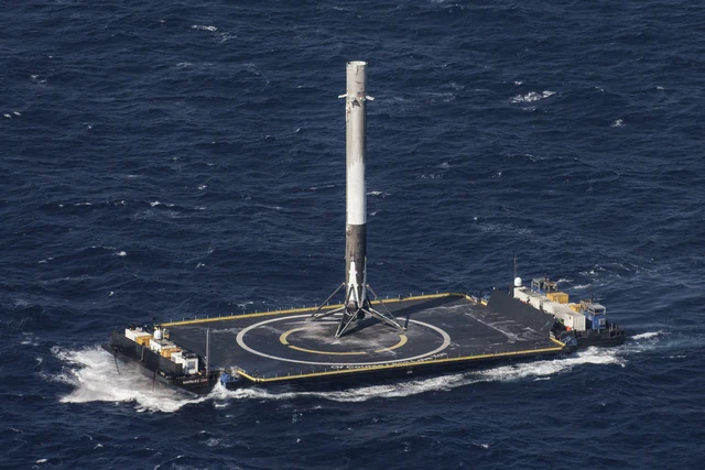 An archival SpaceX CRS-8 photograph shows a Falcon 9 first stage on a drone ship at sea