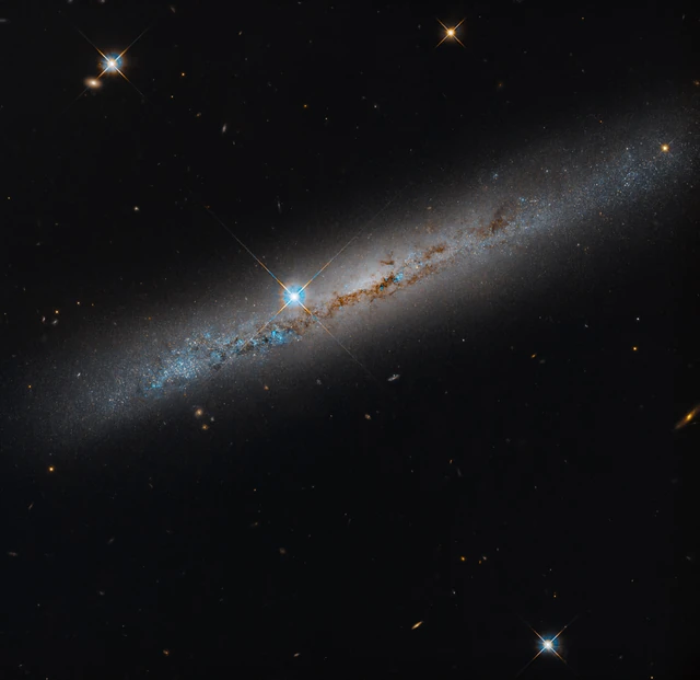 Hubble's NGC 1827 image shows a dusty edge-on spiral galaxy and a bright foreground star beside its central bulge